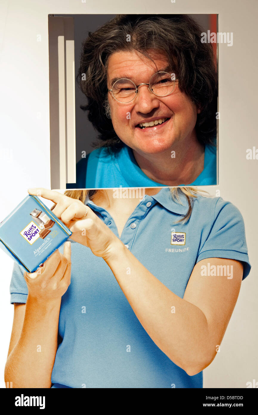 CEO of 'Ritter Sport' Alfred Ritter looks through a hole in a photo wall during the opening of