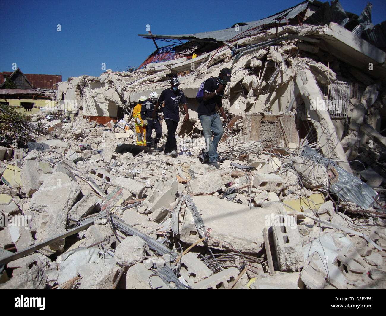 Menschen gehen am Montag (18.01.2010) in Port-au-Prince durch die Trümmer. Die internationale  Gemeinschaft steht im kleinen Karibikstaat Haiti vor einer gigantischen Herausforderung. Während Rettungsteams nach dem verheerenden Erdbeben von Port-au-Prince weiter in den Ruinen nach Überlebenden suchen, treffen sich Dutzende von Hilfsorganisationen aus aller Welt zu Beratungen über d Stock Photo
