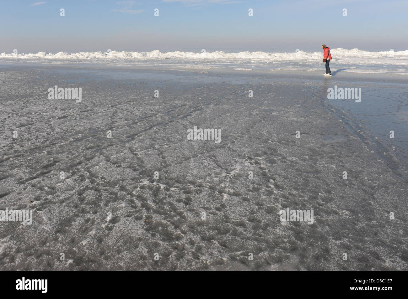 A tourist walks past ice waves at the beach of the coastal resort