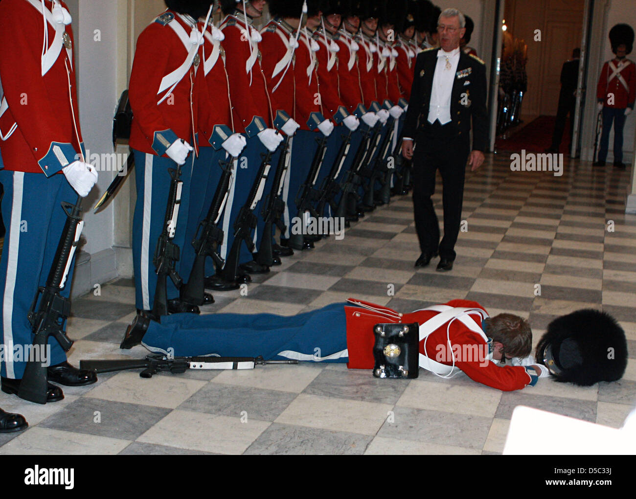 A royal guard lies on the floor after fainting while standing guard at