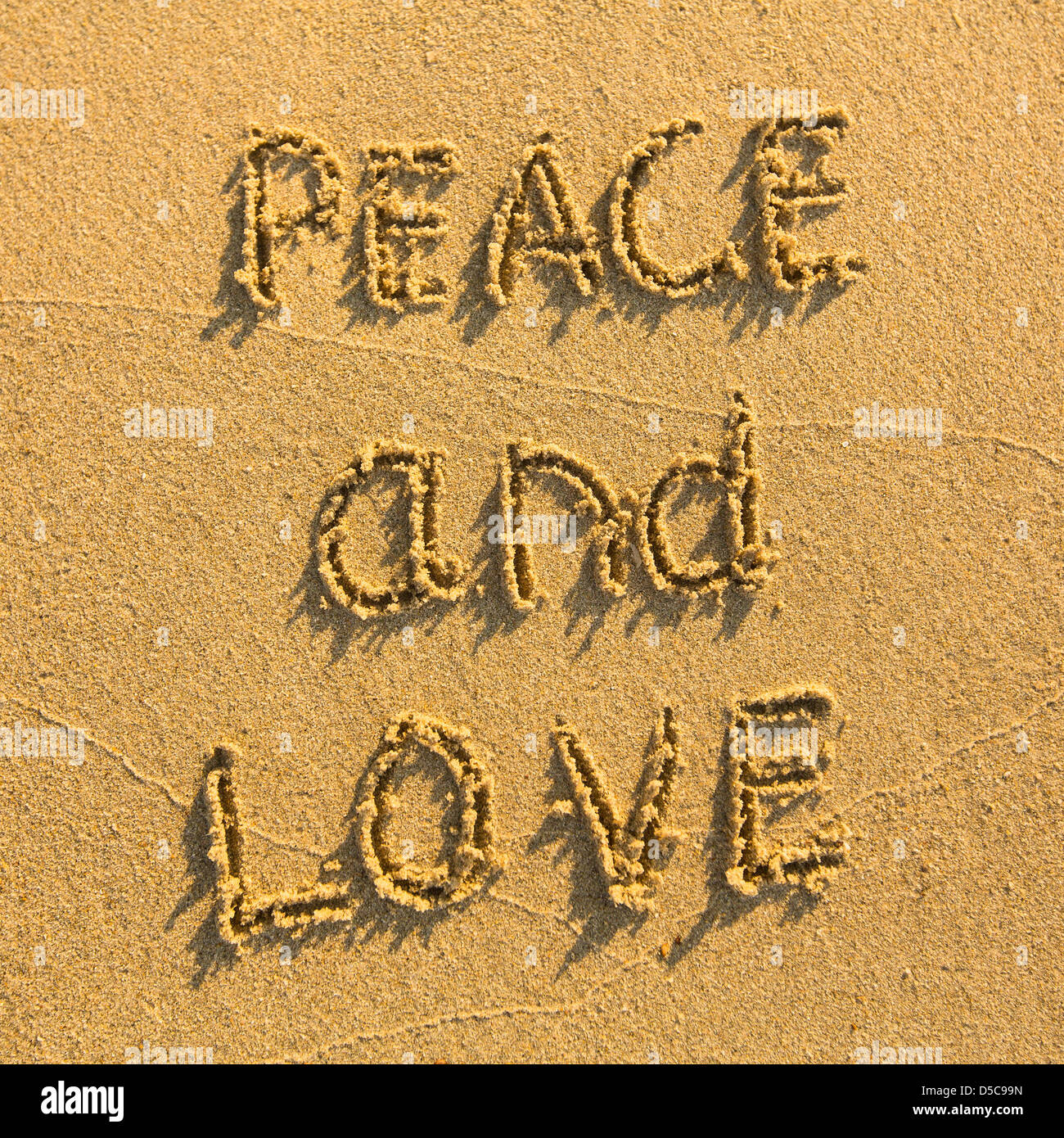 Peace and Love - drawn on the sand of a beach Stock Photo