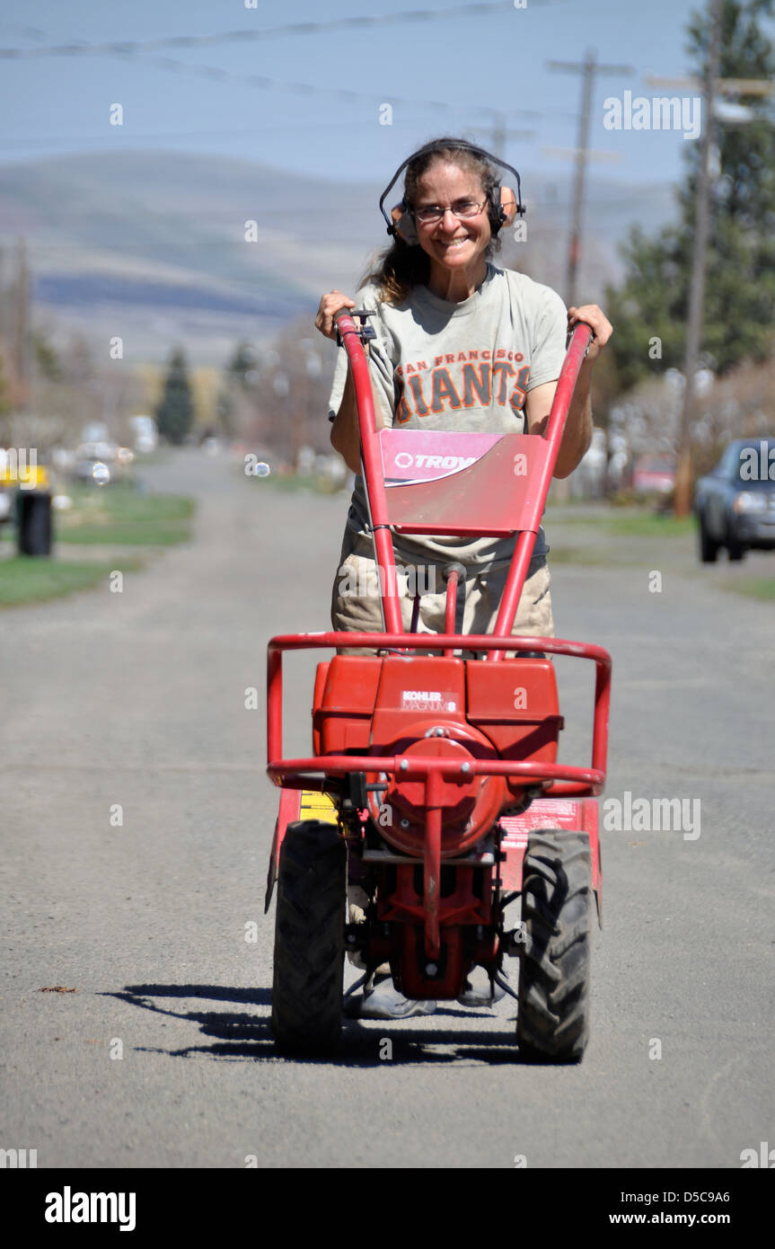 Woman pushing rototiller down a street in Joseph, Oregon. Stock Photo