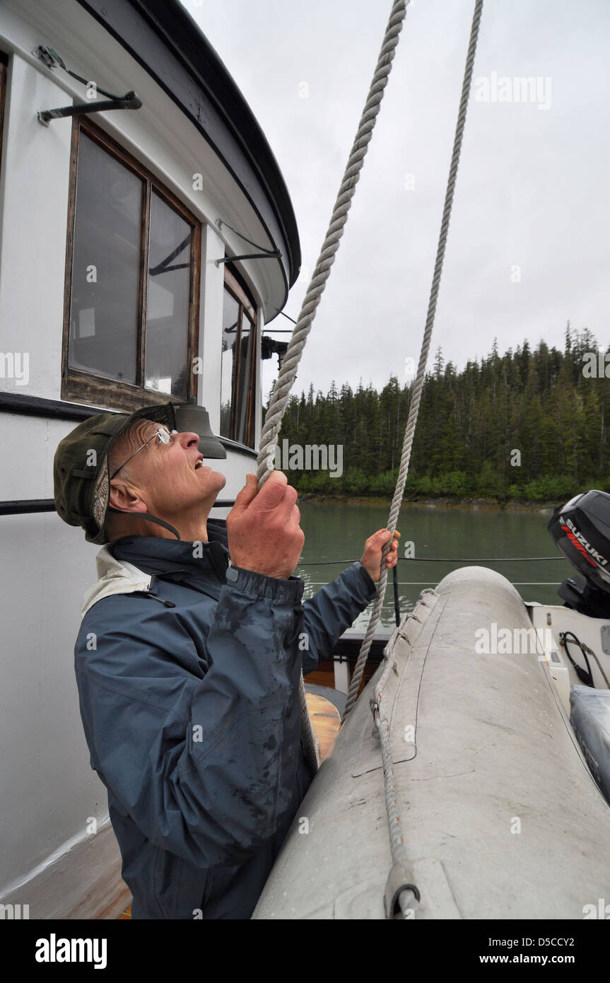 Adjusting ropes holding a dinghy on a the deck of a boat in Southeast ...