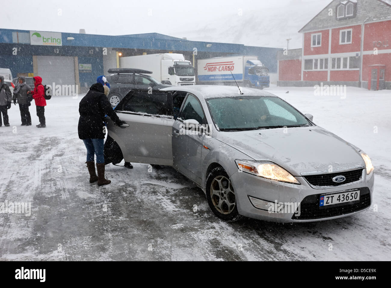 passengers in a snow blizzard getting into a car at the passenger