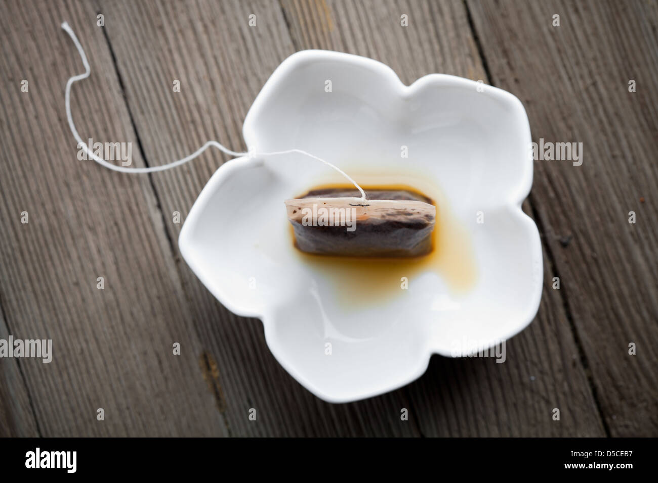 Used tea bag in small white bowl Stock Photo
