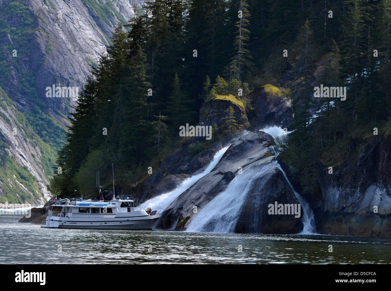 Tour boat by a waterfall in Tracy Arm. Tongass National Forest, Alaska. Stock Photo