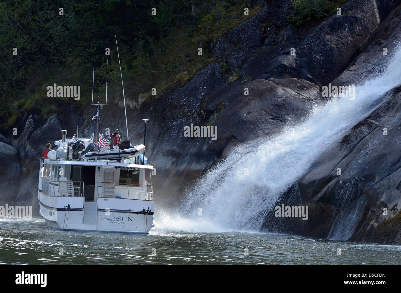 Tour boat by a waterfall in Tracy Arm. Tongass National Forest, Alaska. Stock Photo