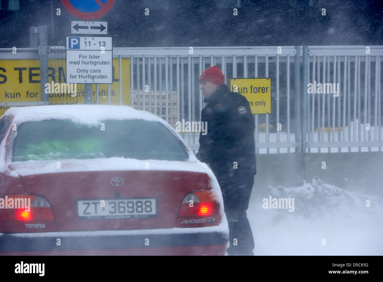 man getting into his car in blizzard covered in snow during winter