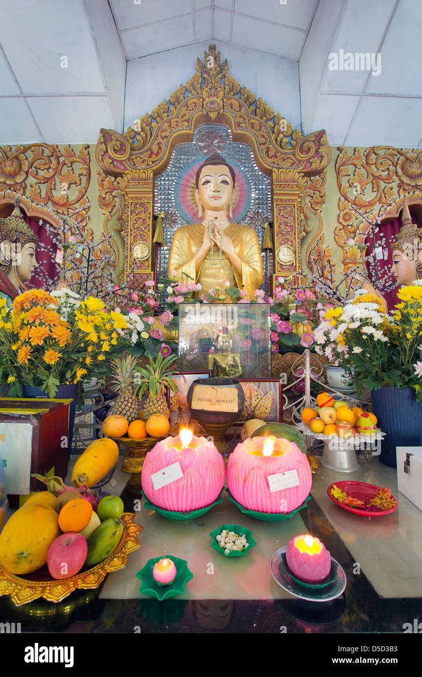 Burmese Temple Buddha Altar with Flowers and Fruits Offerings and Lotus Wax Candles Stock Photo