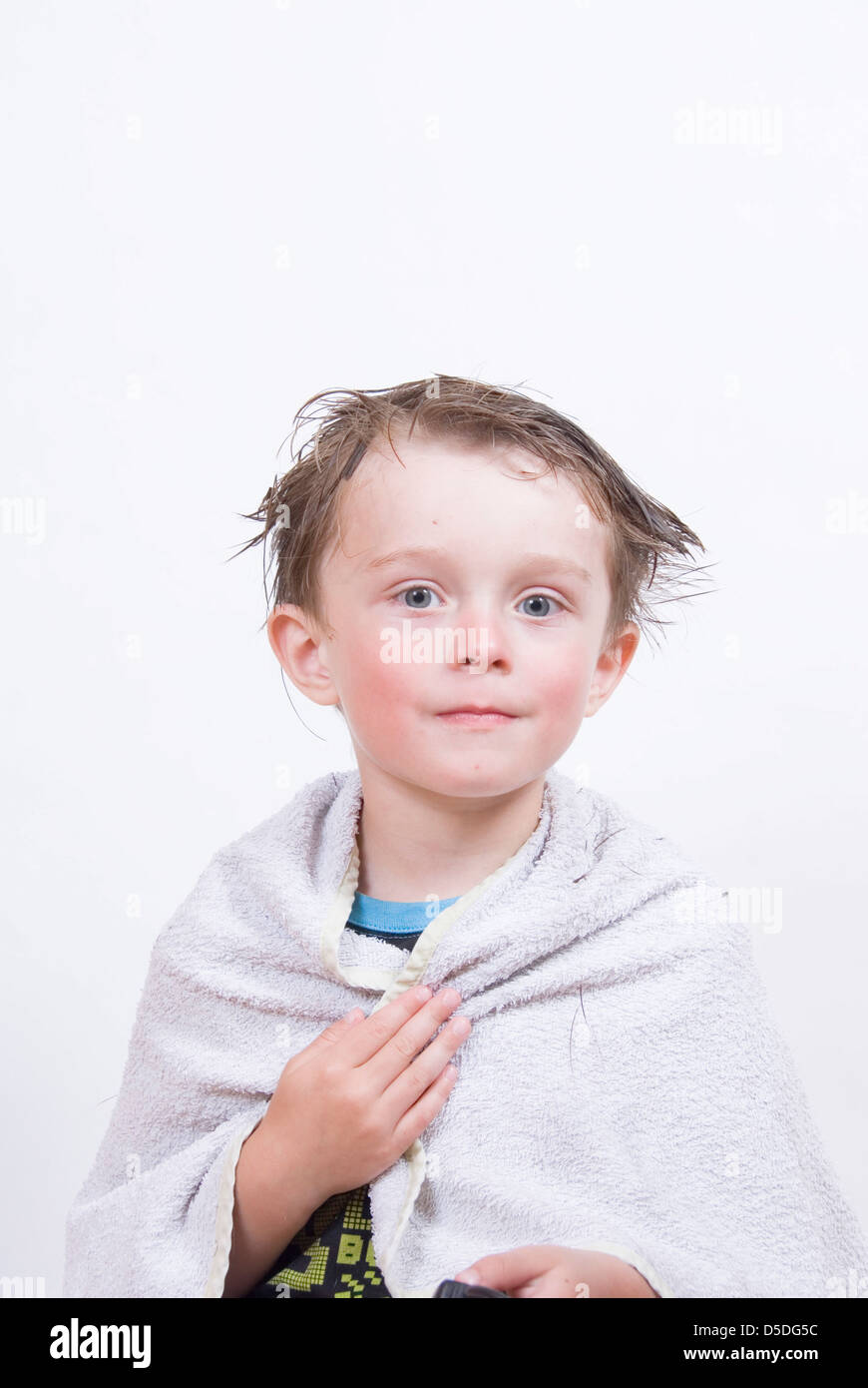 Young boy with messy wet hair wrapped in a towel mid hair cut home