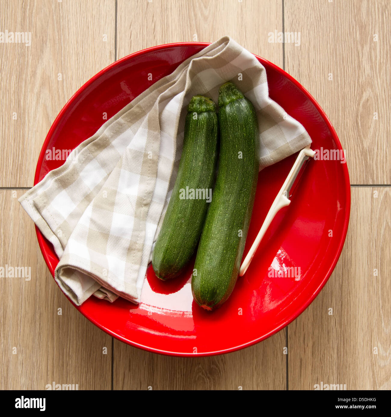 pair of green zucchini on red plate Stock Photo