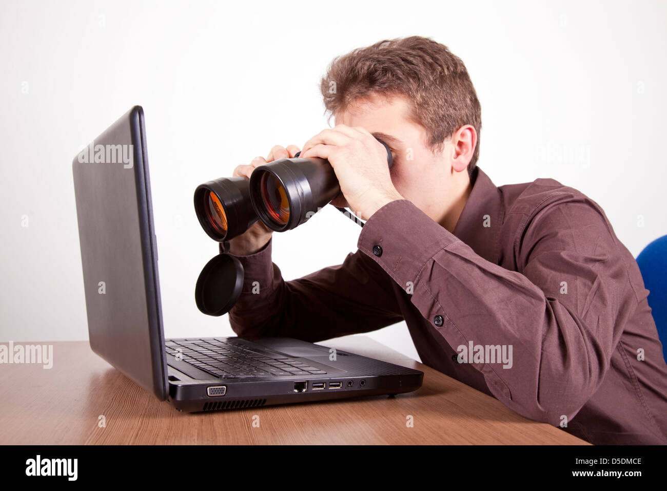 young man searching on the web at a laptop with binoculars Stock Photo ...