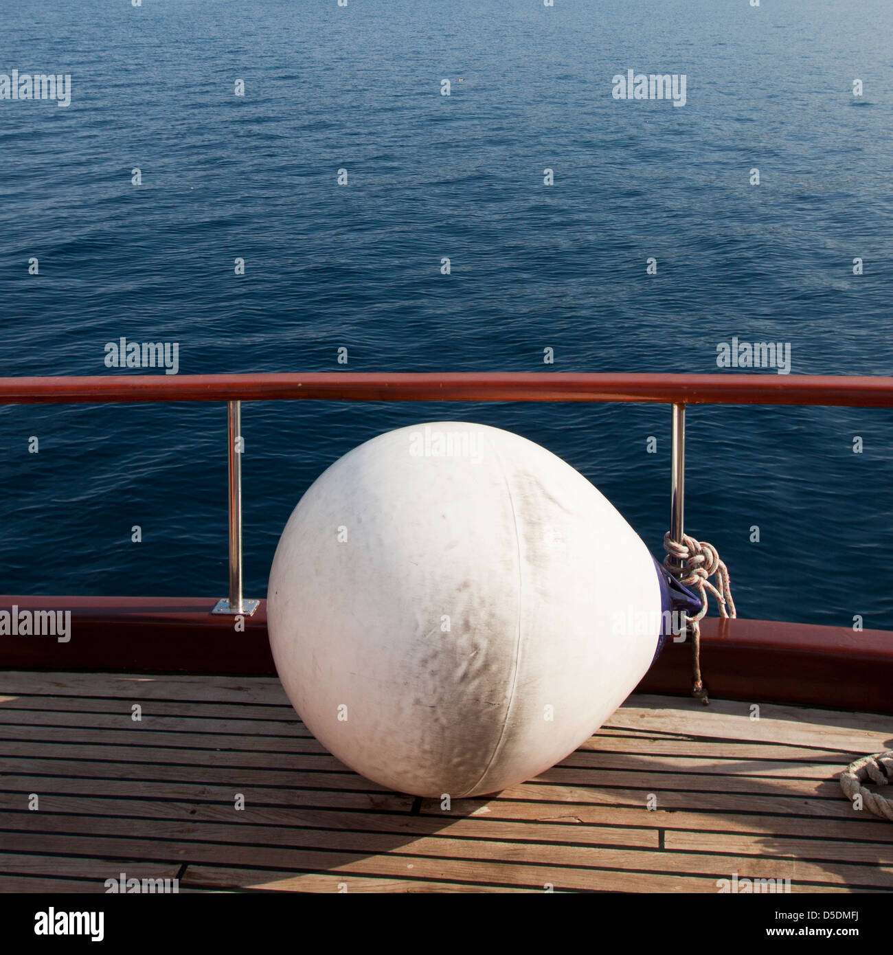 A white mooring buoy attached on the side of a ship on deck looking out into the sea Stock Photo