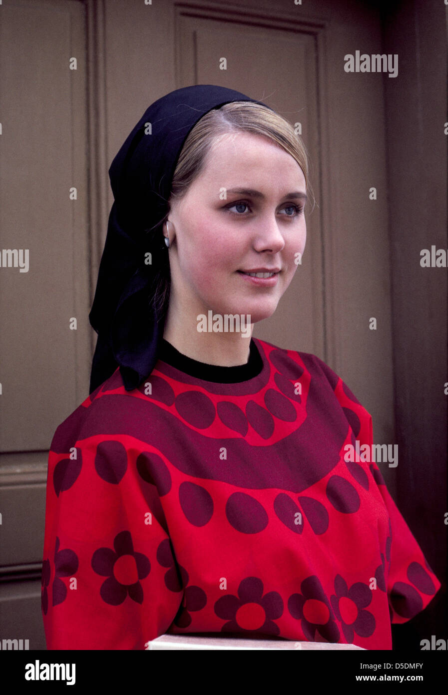 A pretty Norwegian girl wearing a dark headscarf and a colorful blouse poses for an informal portrait in Scandinavia. Stock Photo