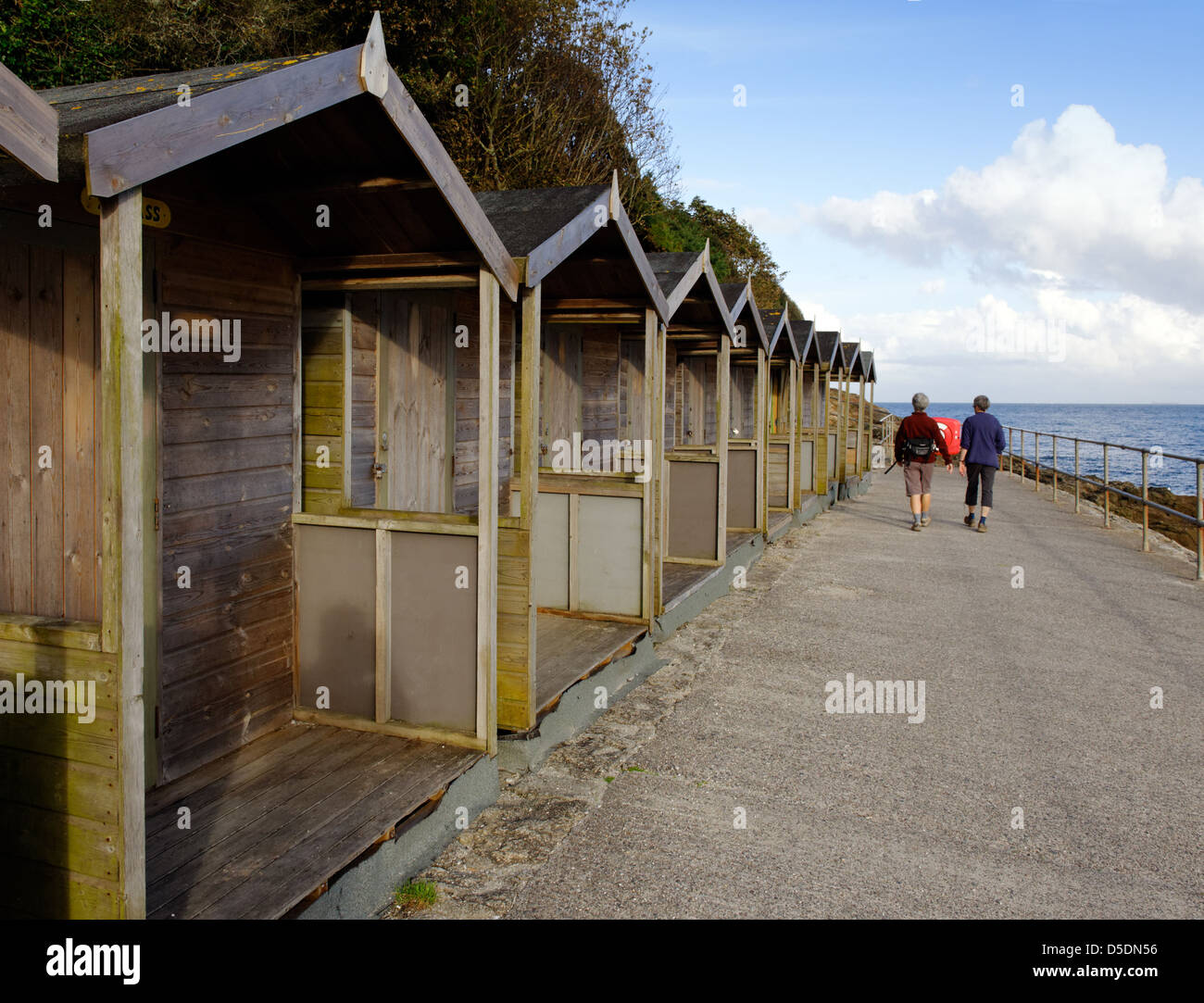 Beach huts and walkers on the coast path at Swanpool, Falmouth, Cornwall Stock Photo