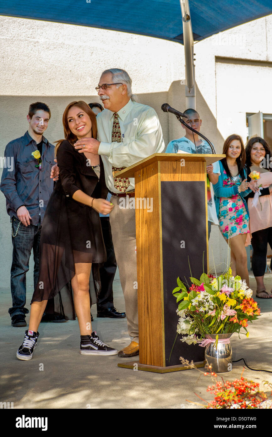 The principal of a Southern California continuation high school. congratulates a casually dressed female student at graduation. Stock Photo