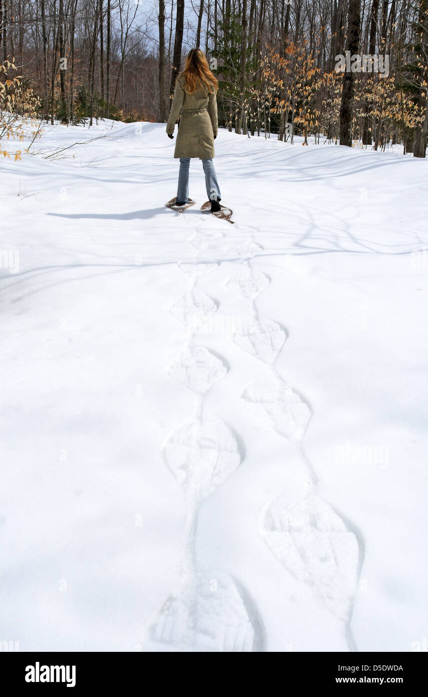 Woman walking in snow shoes in winter forest. Stock Photo