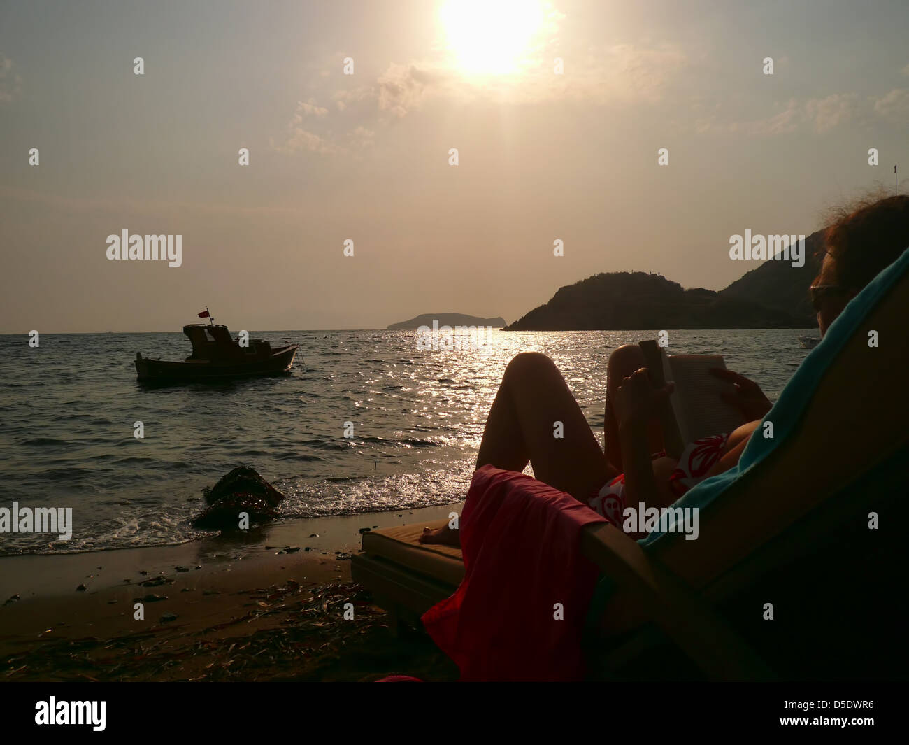 Reading on beach at dusk Stock Photo Alamy