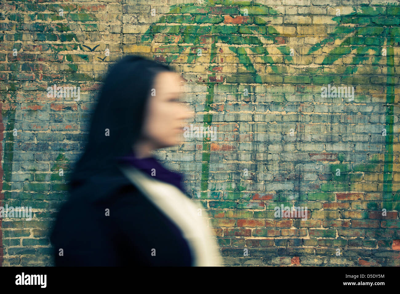 Woman walking by painted wall Stock Photo