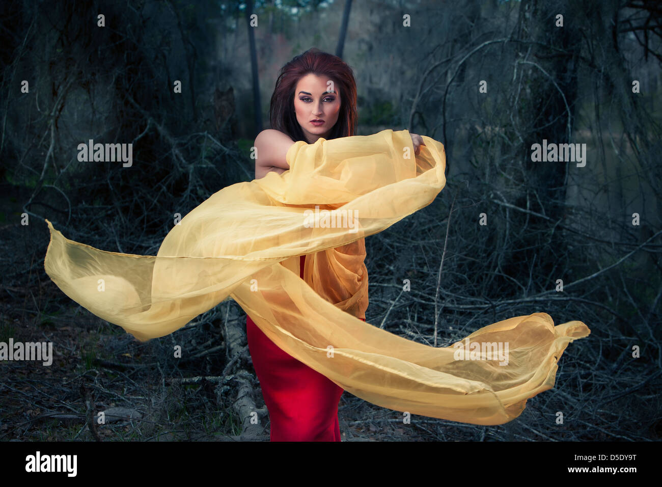 Woman swirling yellow cloth in woods Stock Photo