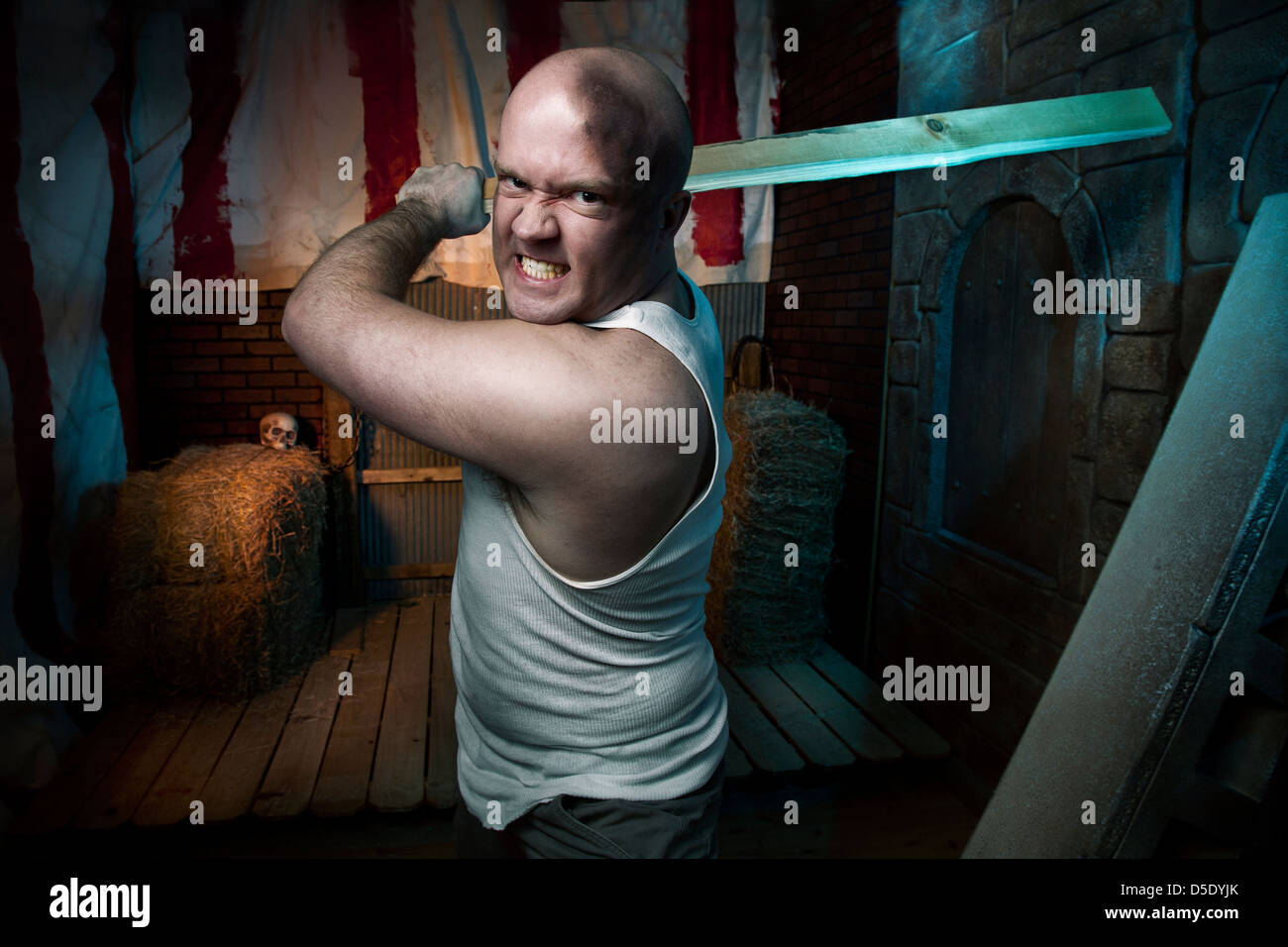 Man attacking with board in tented dark alley Stock Photo