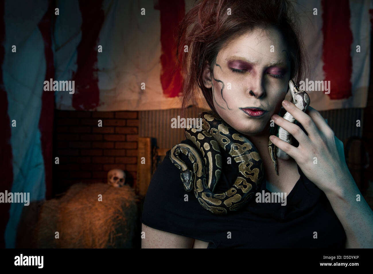 Woman with snakes around neck in dark tented alley Stock Photo