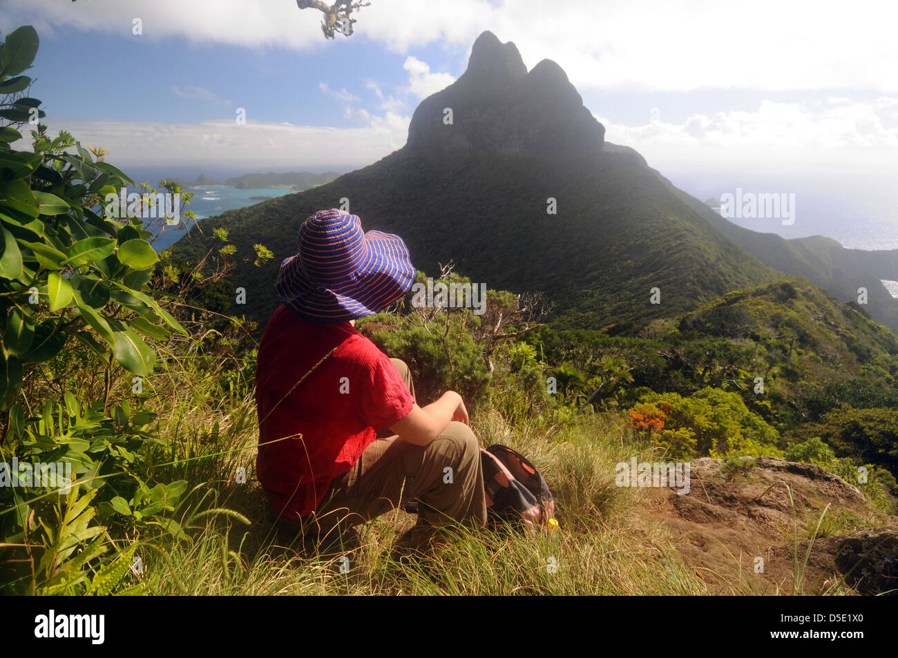 Female hiker resting halfway up Mt Gower, with view over Mt Lidgbird, Lord Howe Island, Australia. No MR Stock Photo