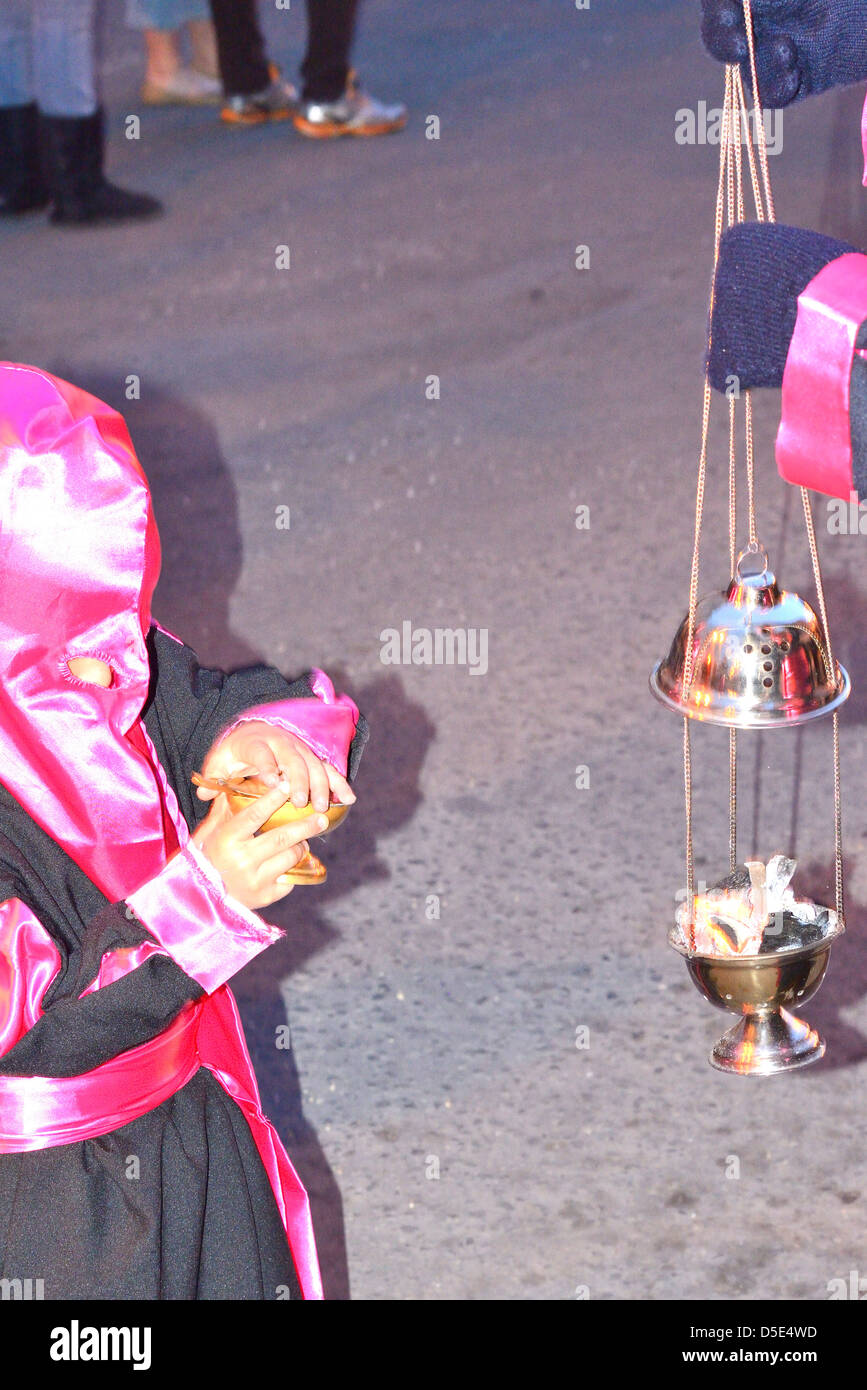 Child recharging an incense dispenser during a catholic procession for