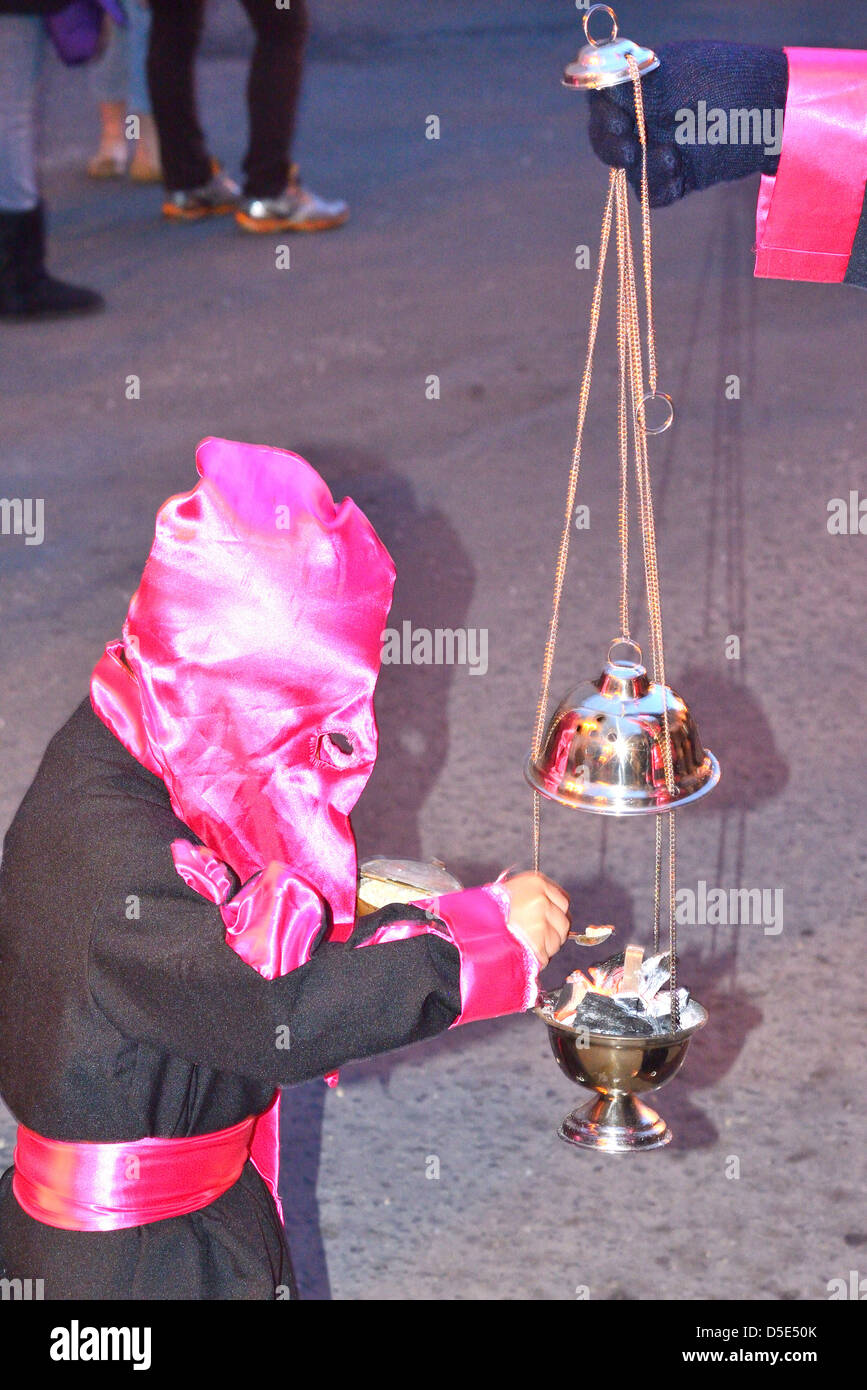 Child recharging an incense dispenser during a catholic procession for