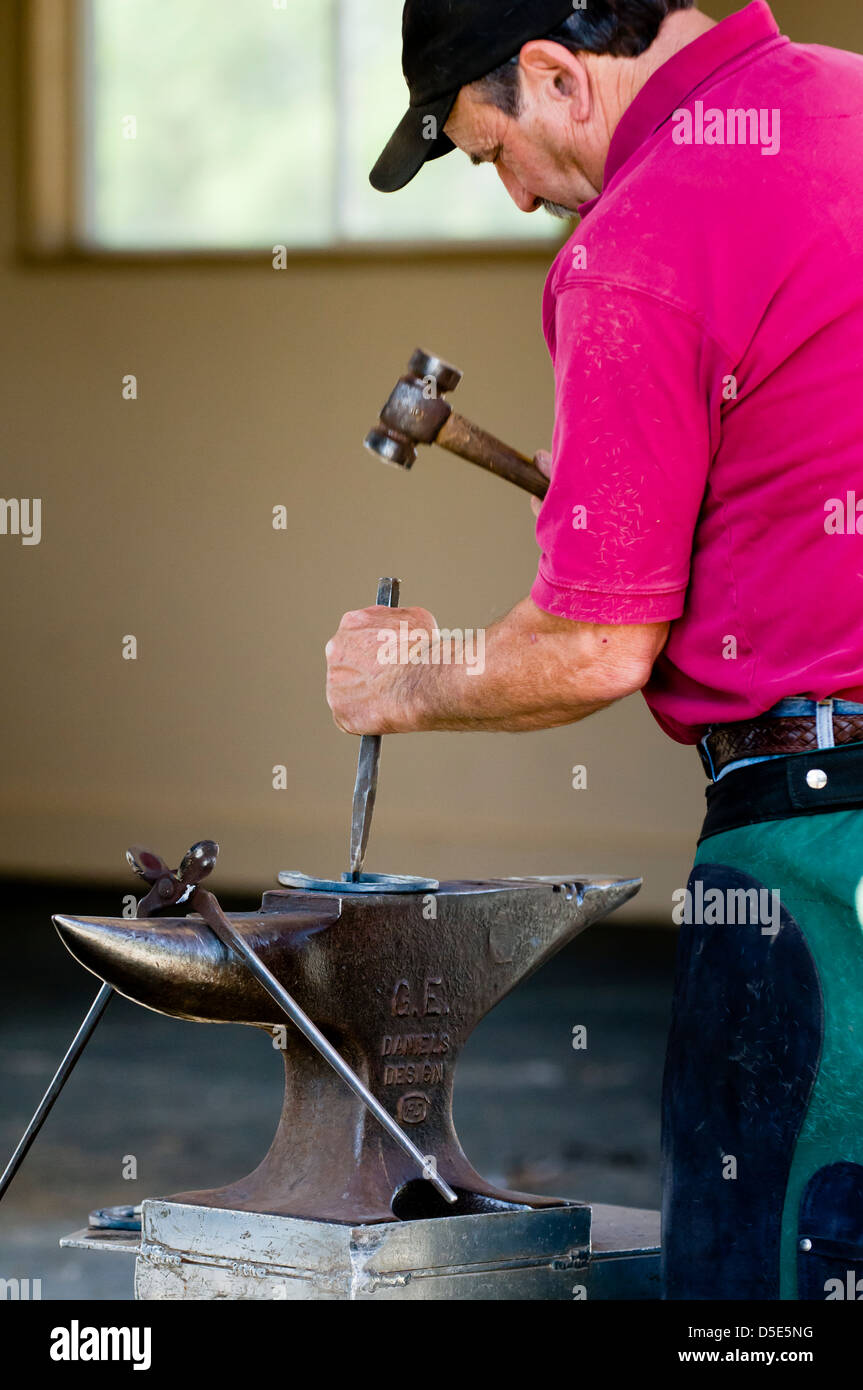 Farrier hammering a horseshoe on an anvil. Brentwood, California, USA
