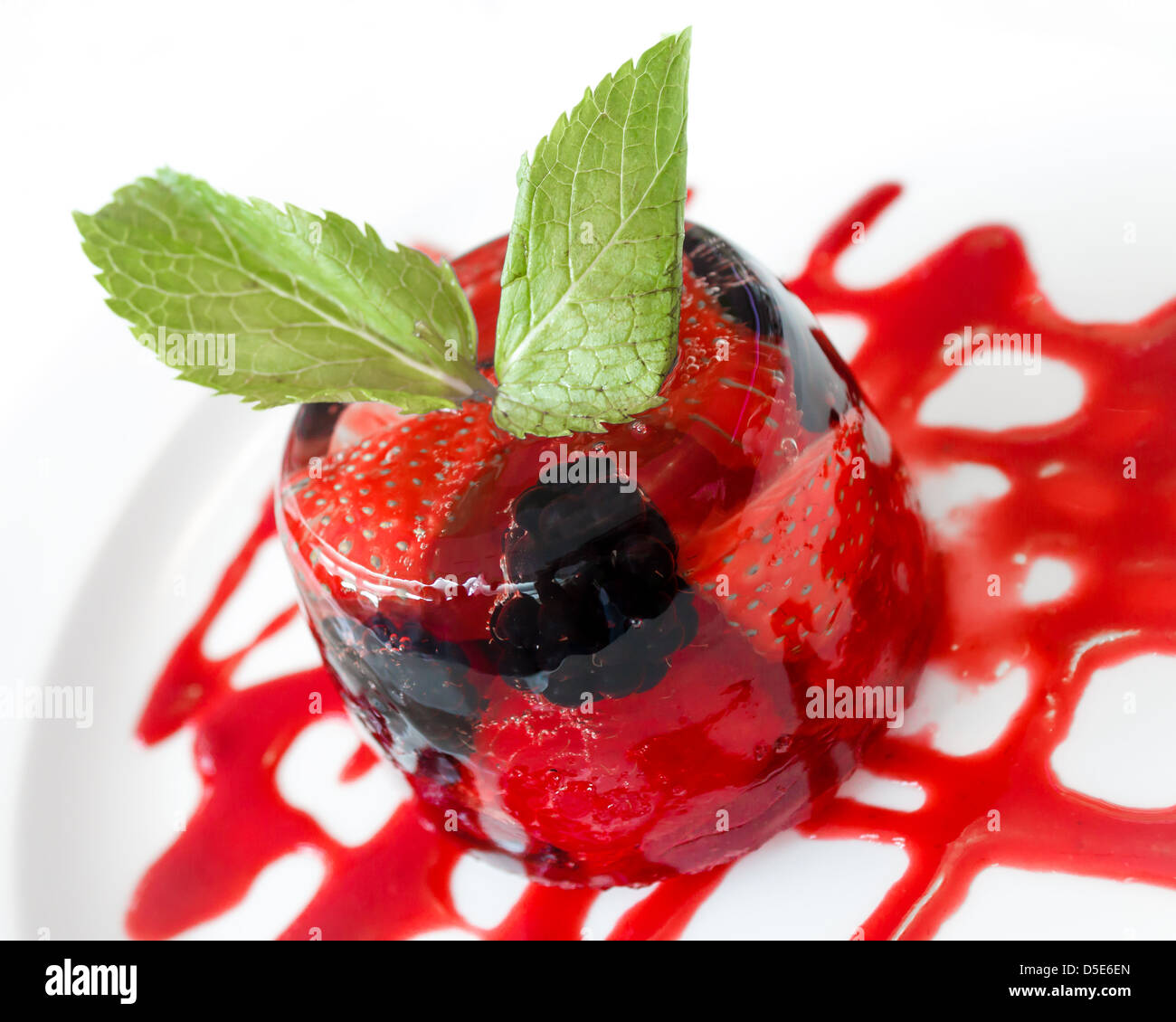 Summer Berries in Jelly Dessert, with red coulis and fresh mint leaves