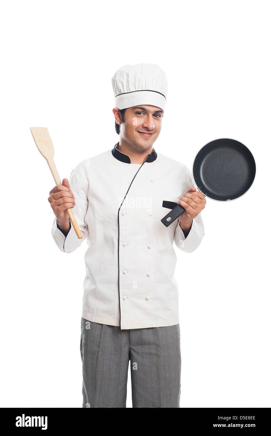 Portrait of a male chef holding a frying pan with spatula and smiling Stock Photo
