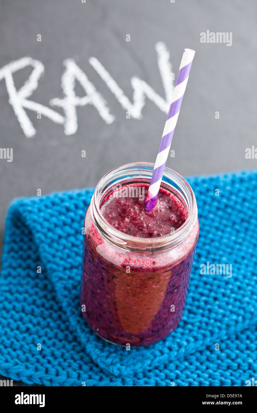 Closeup of blueberry smoothie in glass with striped straw resting on ...