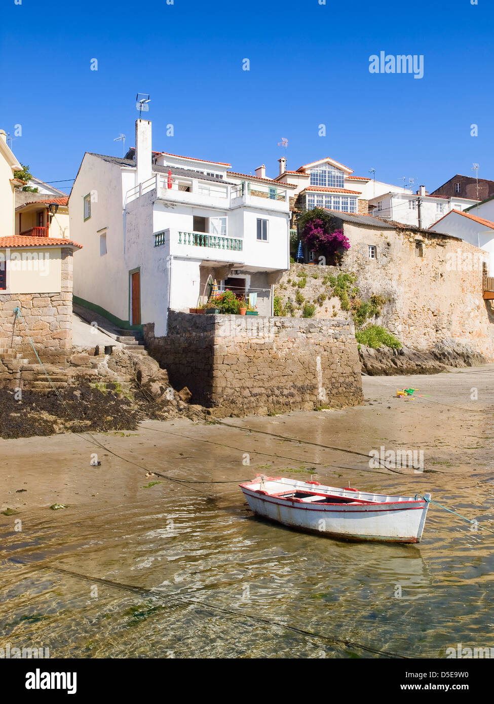 Houses on the sea shore with a boat in the foreground. The photo is taken in a fishing village called 'Redes', in Galicia, Spain Stock Photo