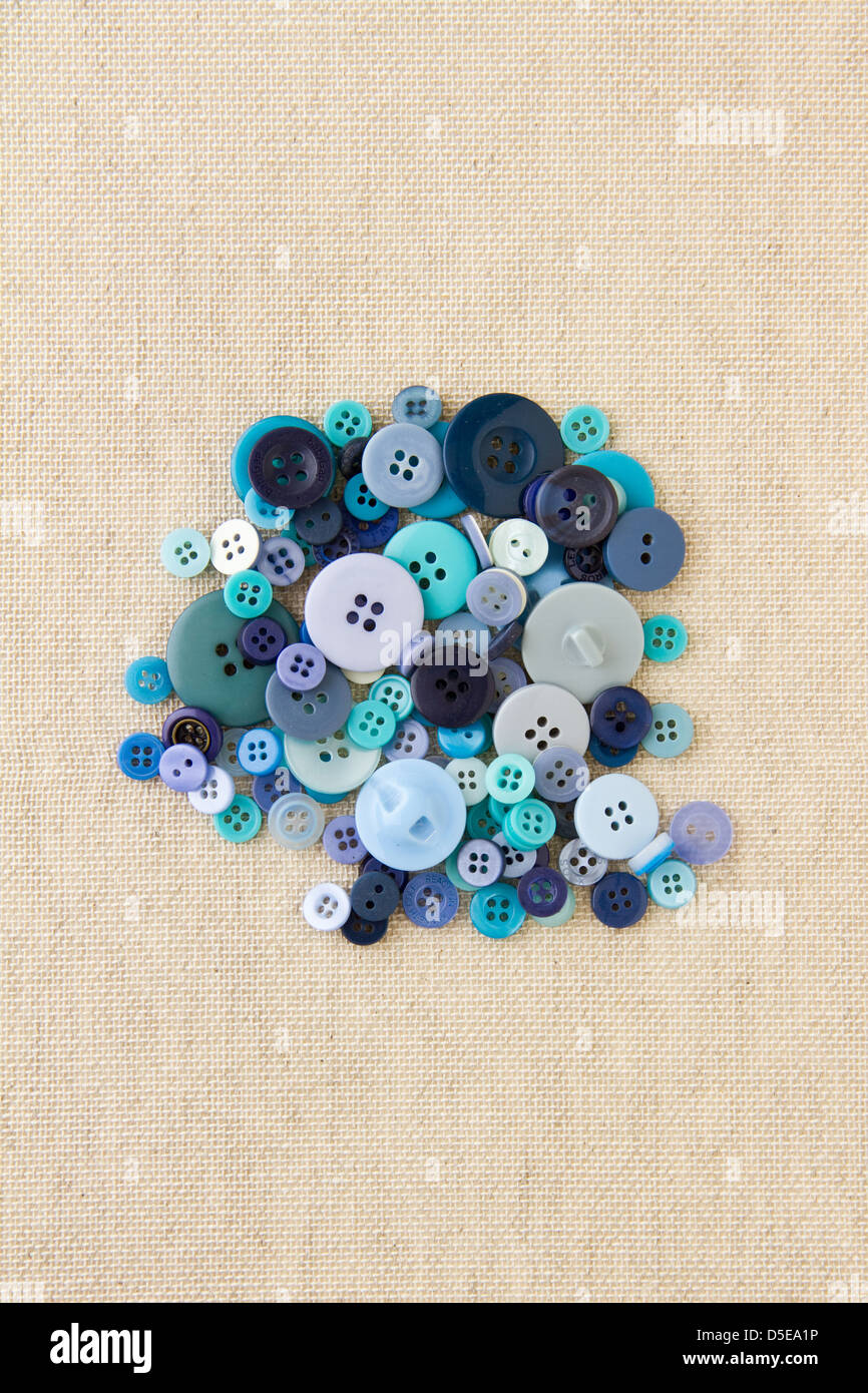 Many blue sewing or clothing buttons piled up on hessian Stock Photo