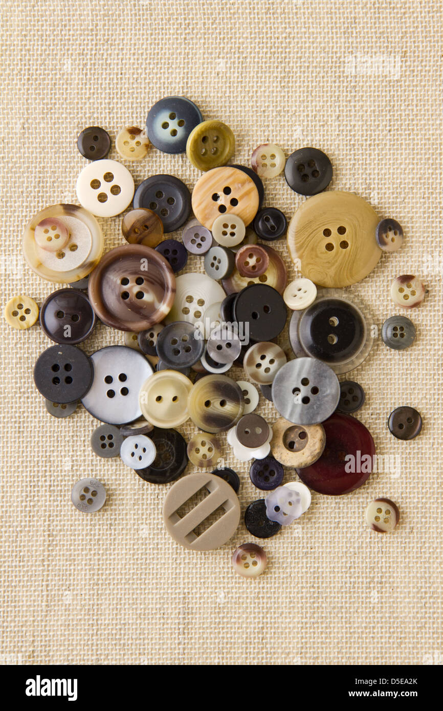 Many neutral brown sewing or clothing buttons on hessian Stock Photo