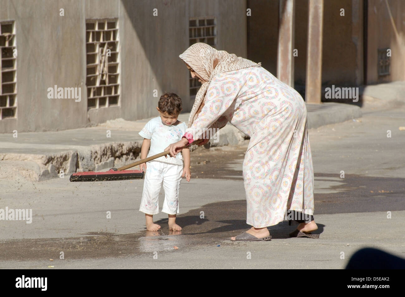 An elderly woman with a child washed streets, Palmyra, Syria  Stock Photo