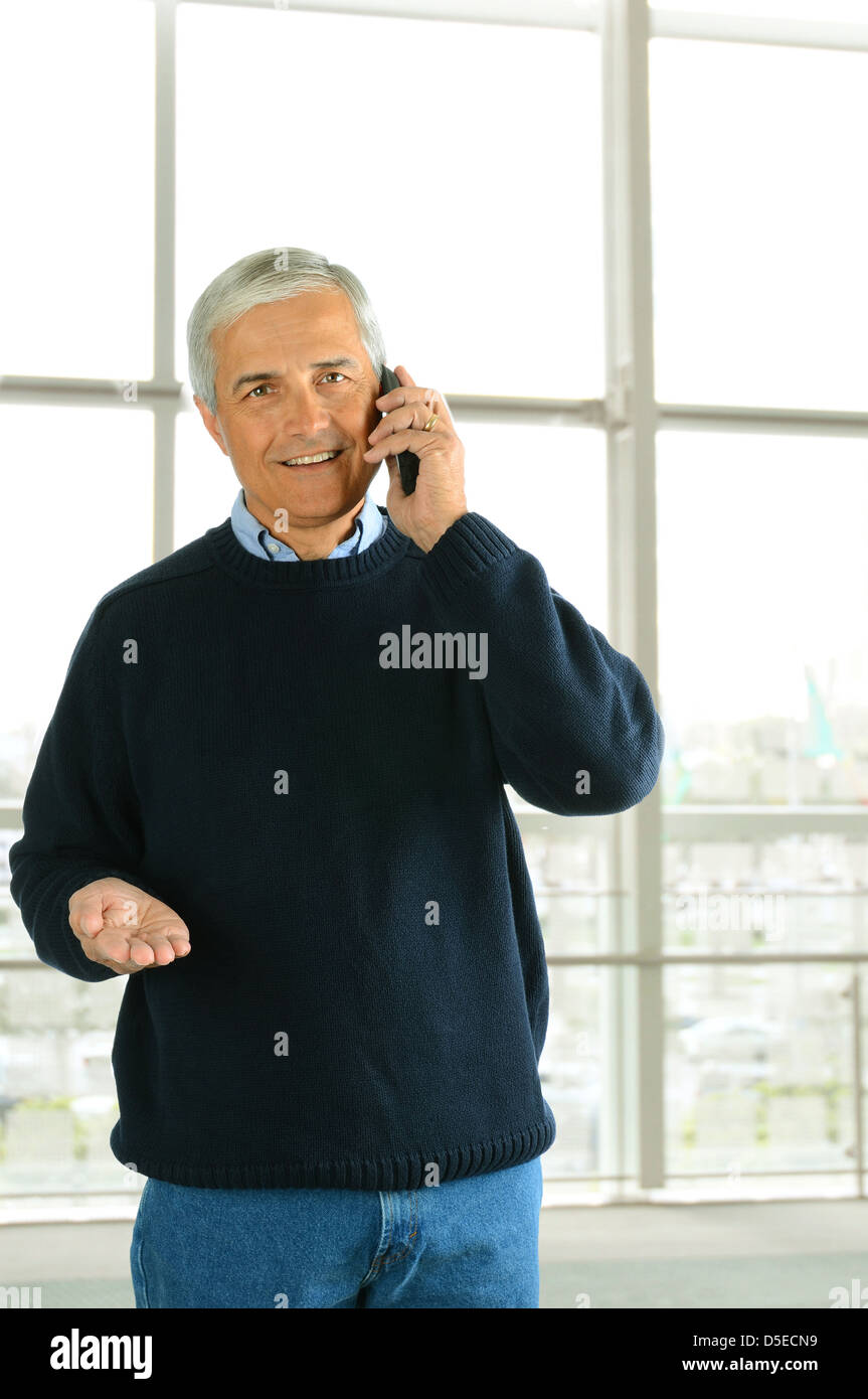 Closeup of a casual businessman in a modern office talking on his cell phone. Vertical Format. Stock Photo