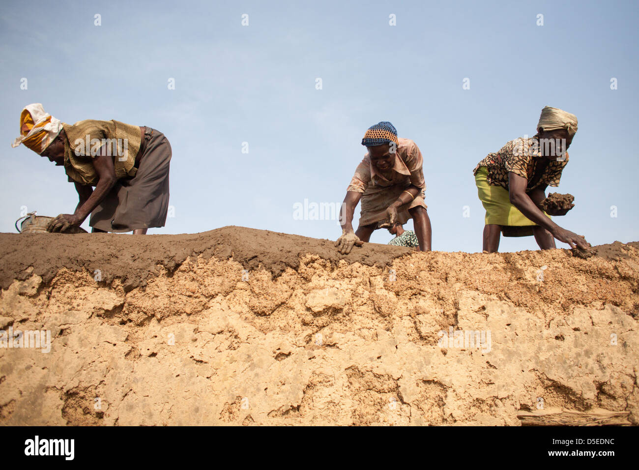 Women makes repairs to the roof of a house in Nandom, Ghana. Stock Photo