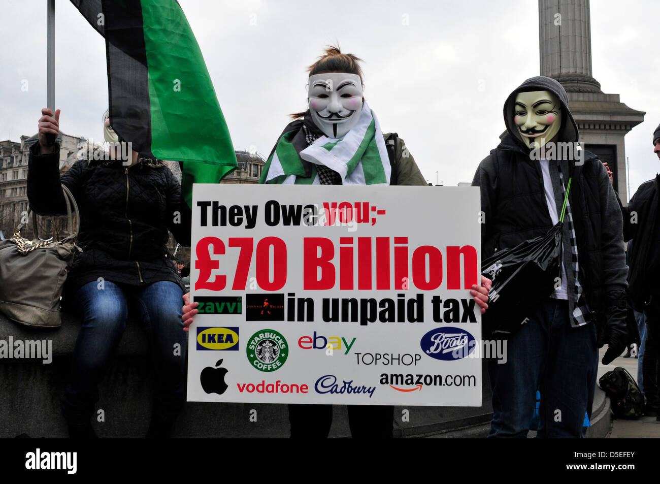 An anonymous protesters holds a banner reading 'they owe you £70 billion in unpaid tax', referring to the companies who allegedly do not pay corporate tax in UK. Stock Photo