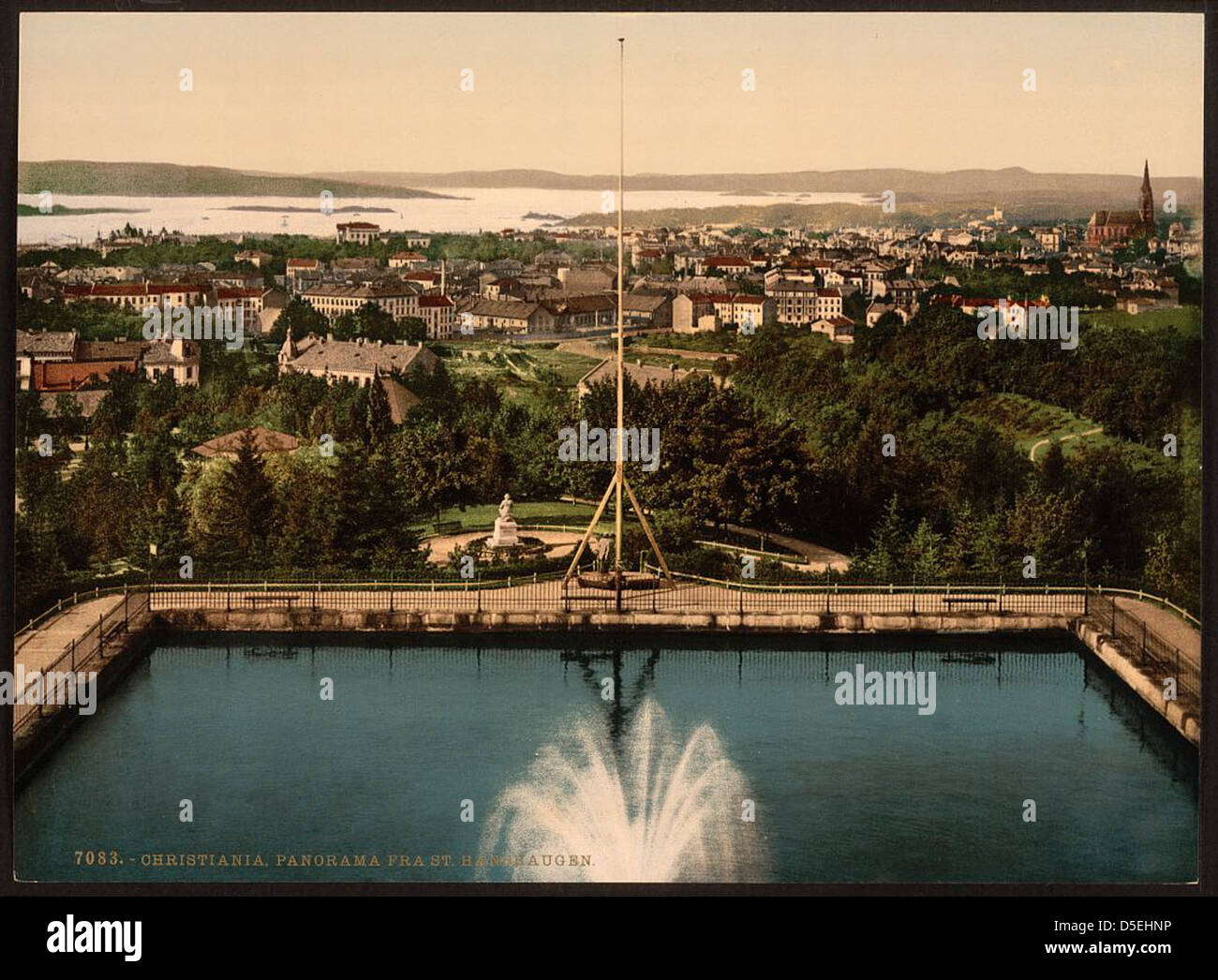 A panoramic, colorized image of Christiania (now Oslo), Norway, from St. Hanshaugen hill. The view shows the Oslofjorden, fountains, and the surrounding landscape, providing a historical look at the area in the early 20th century. Stock Photo