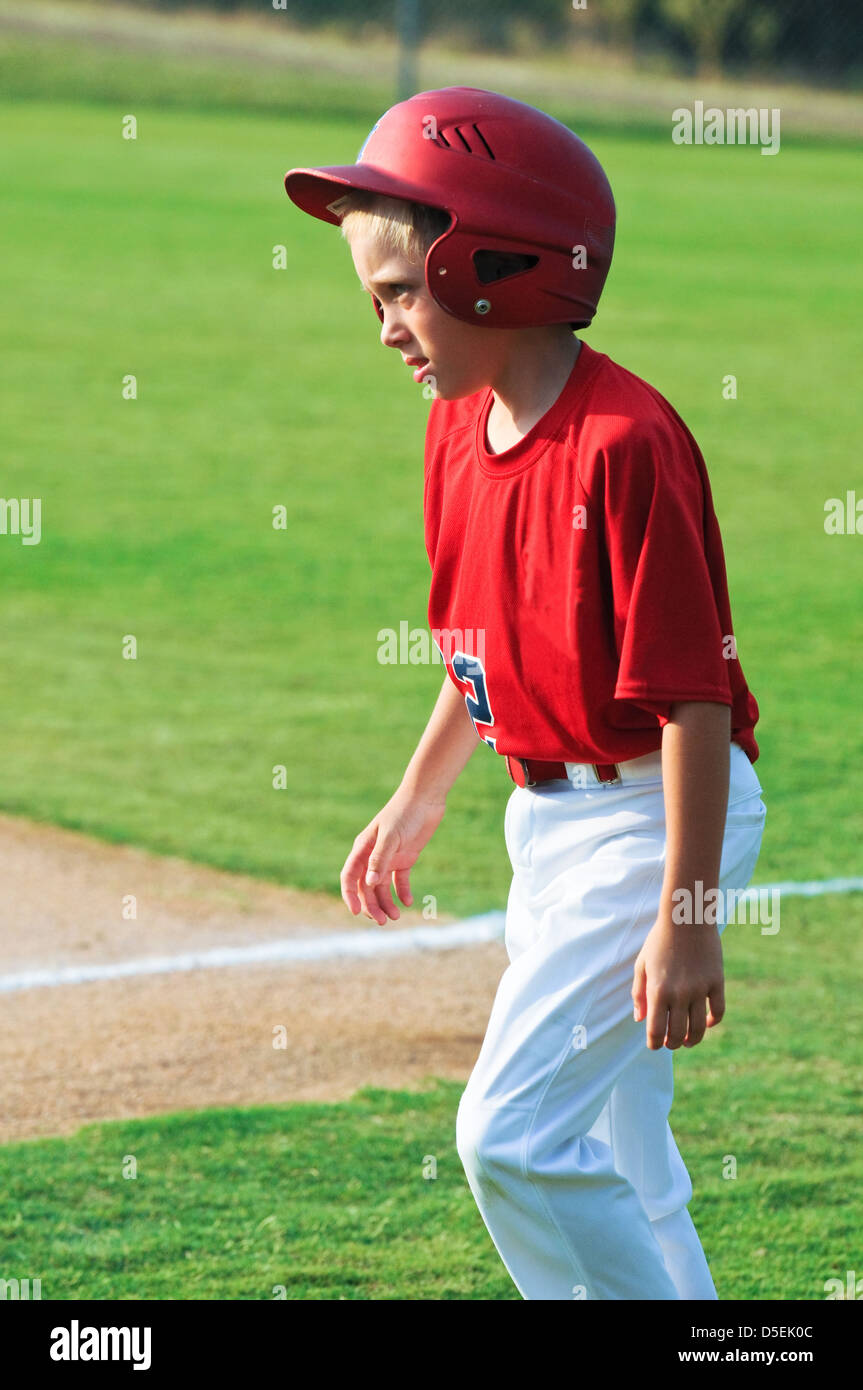 Little league youth baseball boy with helmet walking across ballpark