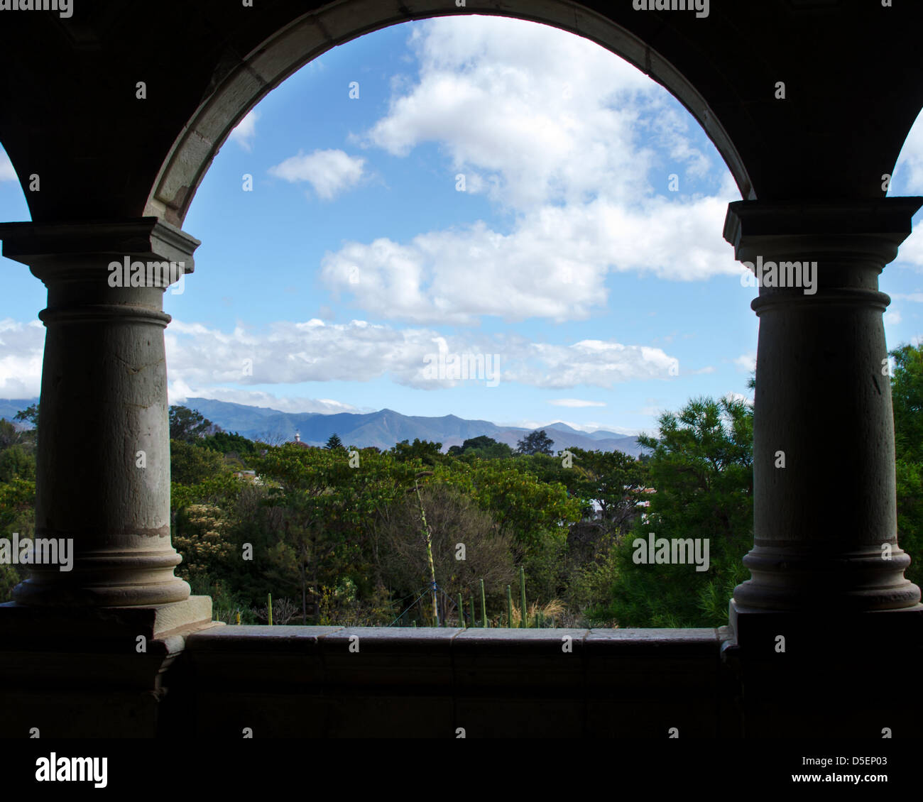 A stone arch in the Centro Cultural Santo Domingo frames a view of the Jardín Etnobotánico and the distant mountains, Oaxaca Stock Photo