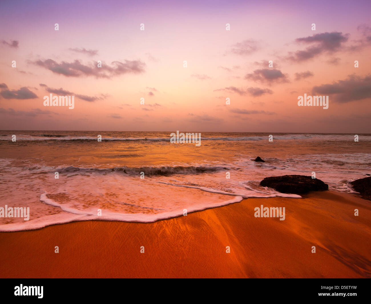 Sunset at tropical beach landscape. Rocks at the ocean coast under evening sun. South India Stock Photo