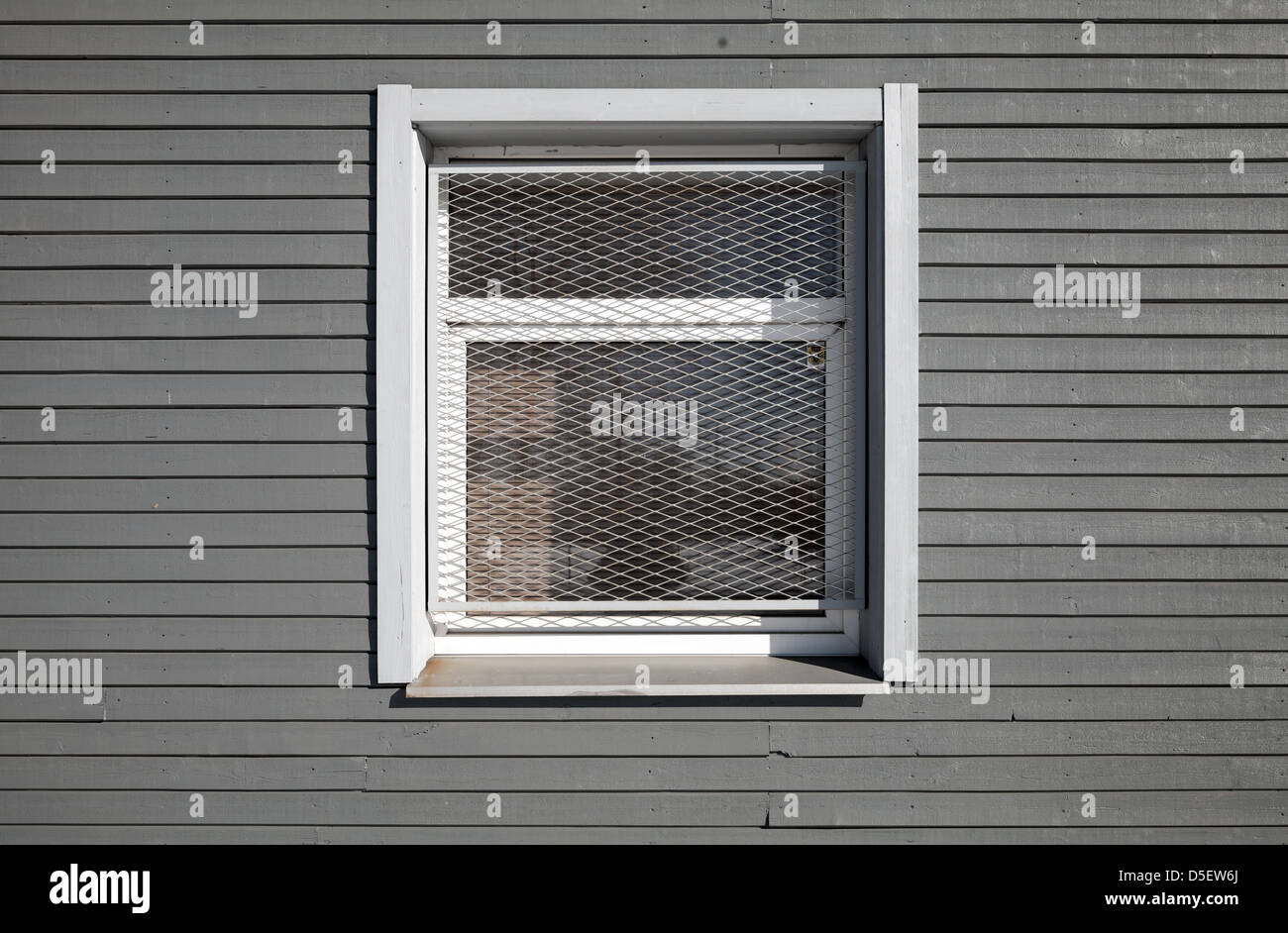 Texture of a locked window with metal grid on the gray wooden wall Stock Photo
