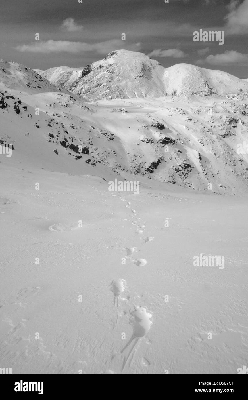 Footprints in the snow on Allen Crags leading towards Great Gable and Seathwaite fell in the English Lake District Stock Photo
