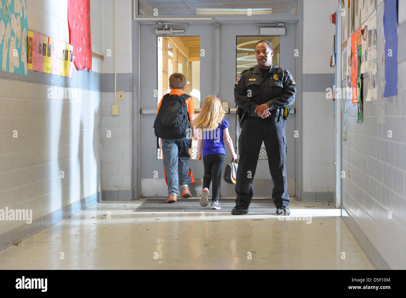 USA Safety in public schools Police officer with boy and girl in school ...