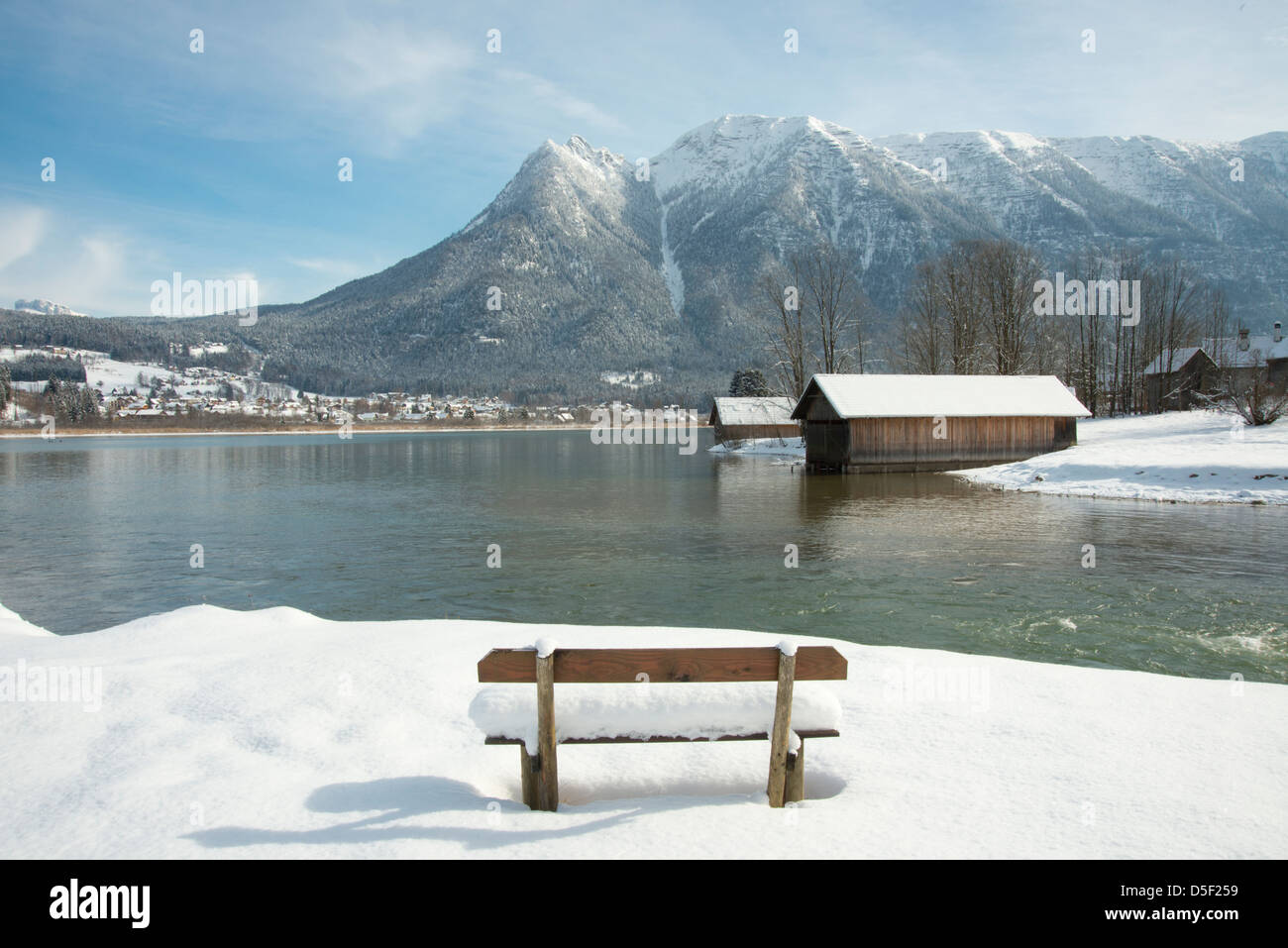 A snow covered bench facing Hallstatter See and the surrounding mountains near the town of Hallstatt, Austria Stock Photo