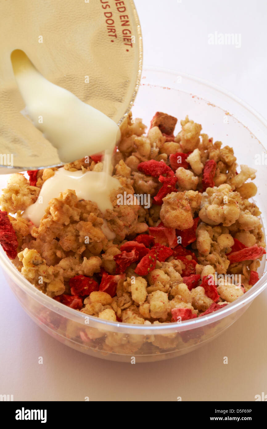 pouring yogurt over topping on tub of Rumblers Oat clusters with