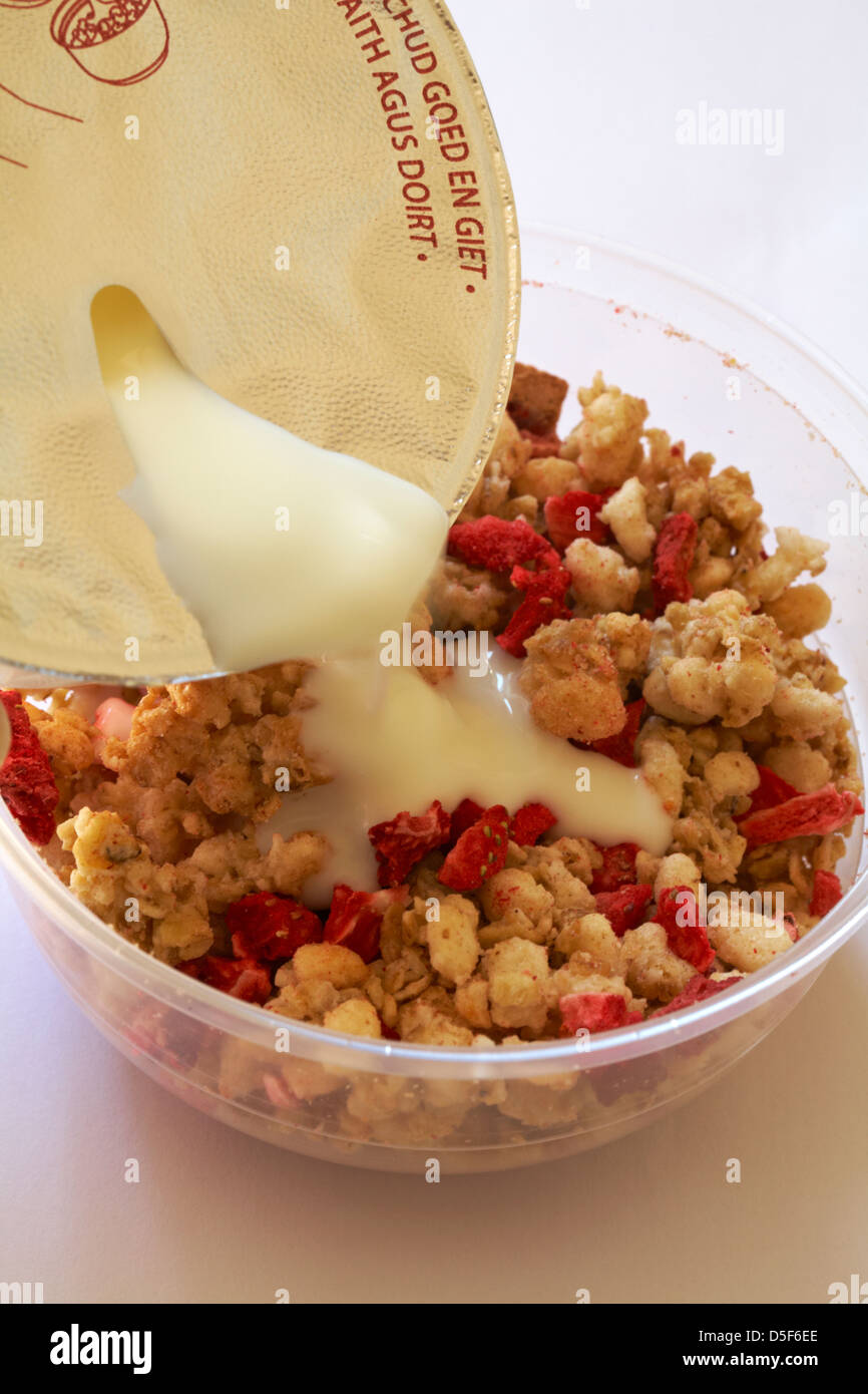 pouring yogurt over topping on tub of Rumblers Oat clusters with